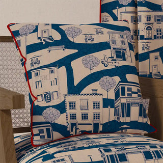 The "French Town Pipin" cushion cover displayed on a chair, showcasing its unique artistic style and how it adds character to a home setting.
