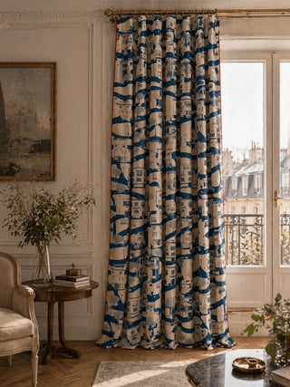 Decorative French Town curtain with blue and white pattern in a room with a window and furniture.