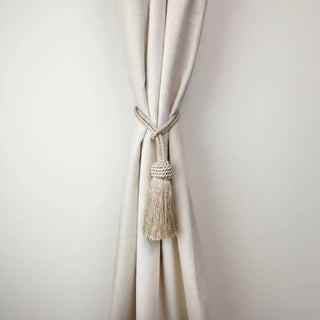 Frosted Silk Handcrafted Curtain Tieback secured around a cream curtain, showcasing the classic tassel design and beige cord.