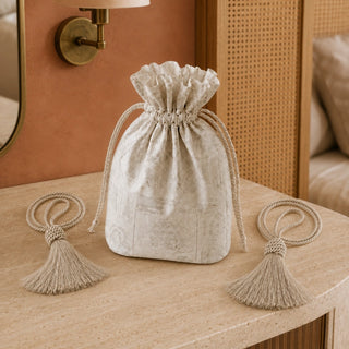 Frosted Silk tiebacks styled beside a printed drawstring gift pouch on a stone-topped console