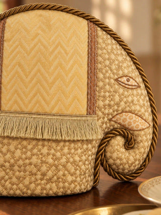 Close-up of the Gajraja tea cosy: diamond-weave gold brocade, a chevron saddle with fringe, an appliqué eye and a rope-curled trunk.