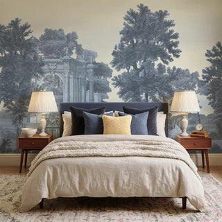 The Garden Charm Blue landscape mural styled behind a navy blue headboard with neutral bedding in a serene bedroom.