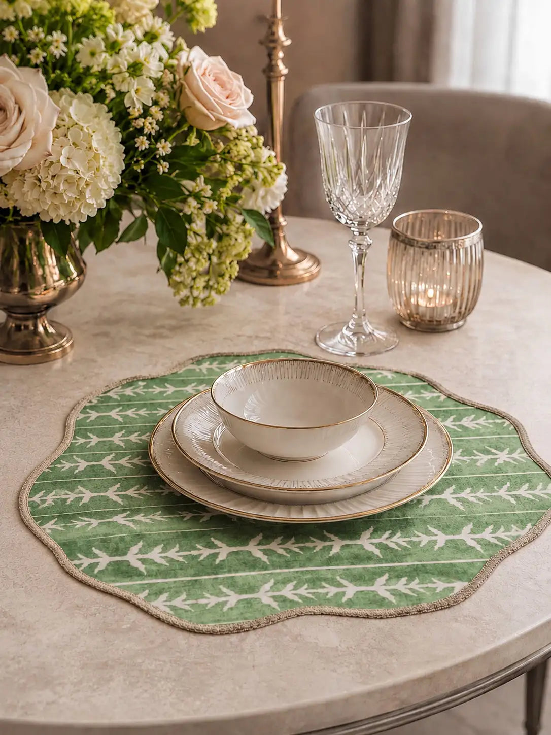 Sage green scalloped placemat on marble beneath white porcelain and crystal glassware