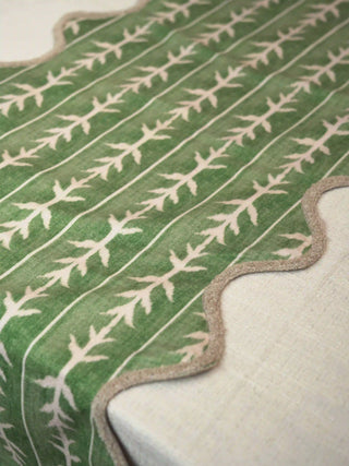 A detailed close-up showing the watercolor green canvas ground and vertical branch stripe design of the table runner.