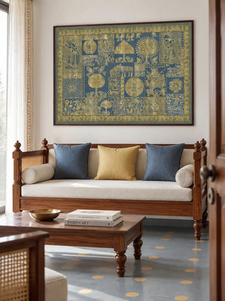 The framed Geet Madhubani wall art displayed above a wooden daybed with mustard and indigo cushions in a living room.