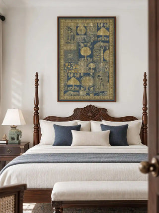 The framed vertical Geet Madhubani wall art displayed above a carved wooden four-poster bed with indigo and cream cushions in a bedroom.