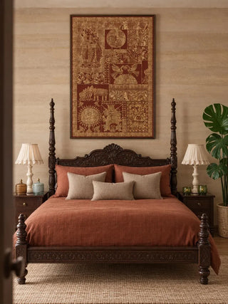 Geet Madhubani embroidered wall art in a slim dark frame above a carved four-poster bed with rust linen bedding and ruffled lamps in a bedroom