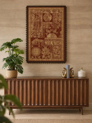 Geet Madhubani embroidered wall art in a dark ball-edged frame above a fluted walnut sideboard with brass swan bookends and a potted plant