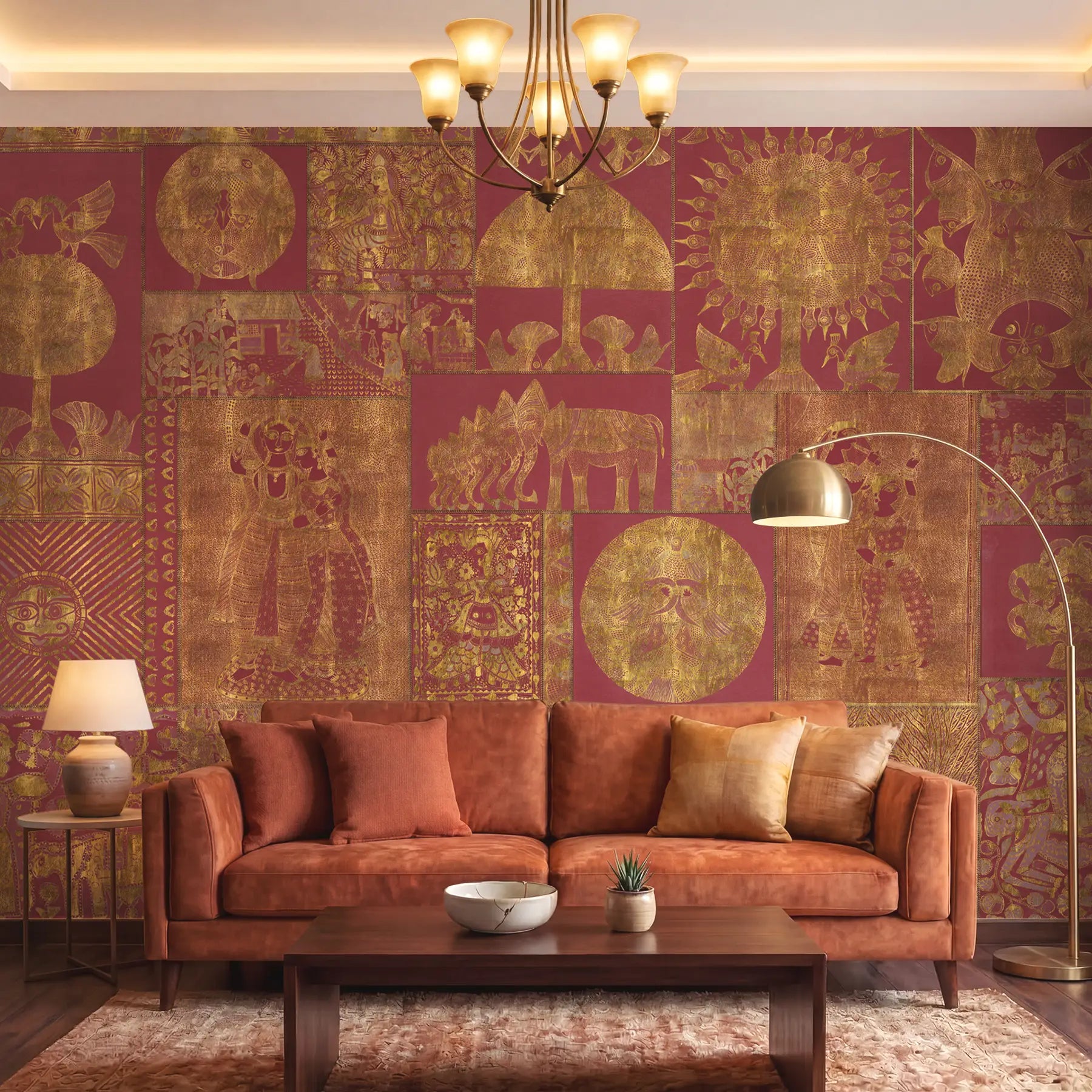 Geet Madhubani wallpaper in terracotta red and gold behind a velvet sofa and brass floor lamp