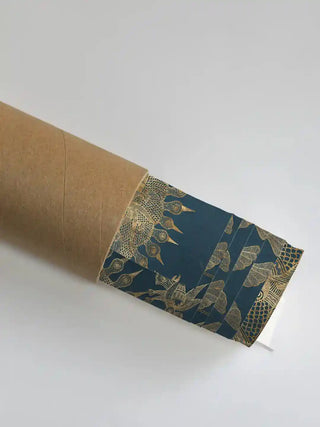 Geet Madhubani wall art print in indigo and gold rolled in a kraft shipping tube, showing the fine gold sun and tree linework.
