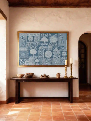 Geet Madhubani wall art in indigo and white, framed in antique gold above a dark wood console with earthen bowls and brass candlesticks in a terracotta-tiled foyer.