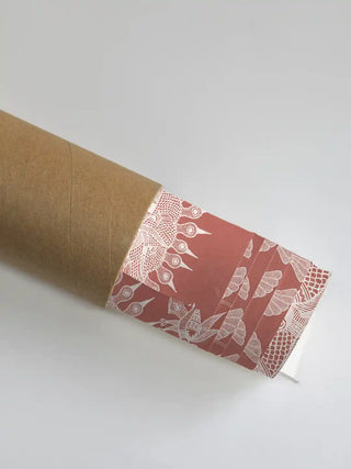 Geet Madhubani wall art print in terracotta and white rolled in a kraft shipping tube, showing the fine white sun and peacock linework.