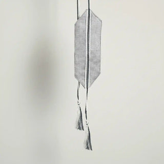 Close-up shot of the Ashline Holdback hanging, highlighting the pointed fabric ends and the two-tone black and white cords.