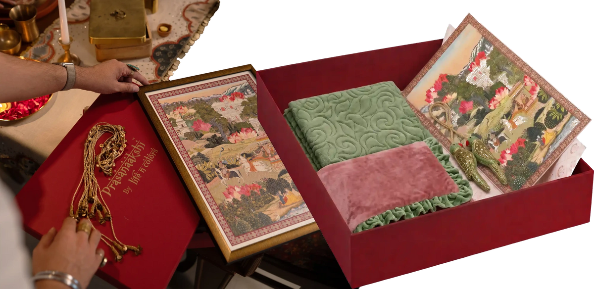 Hands opening a gift box holding framed Indian wall art and a quilted sage throw