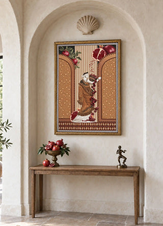 The Gilded Mythos embroidered wall art displayed in an arched plaster alcove above a wooden console styled with fresh pomegranates.
