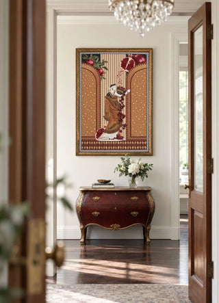 The Gilded Mythos embroidered wall art framed above a bombe chest beneath a crystal chandelier in an entrance hallway.