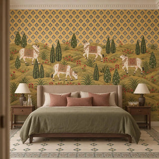 The Gokul Reverie wallpaper mural behind an upholstered bed with an olive throw and rose cushions, white cows grazing on the hills view-bedroom