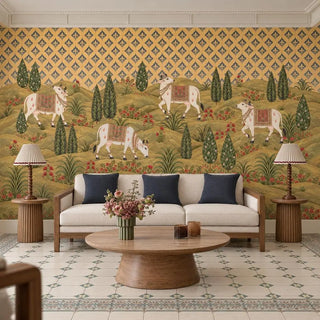 The Gokul Reverie wallpaper mural with adorned white cows behind a cream sofa with navy cushions and a round wooden coffee table view-livingroom