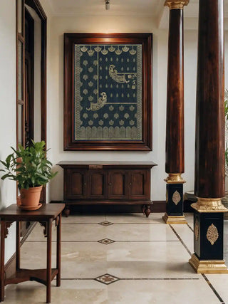 Golden Crest wall art in midnight blue and gold, framed in dark rosewood above a teak sideboard beside polished columns with brass bases in a marble-floored entryway.