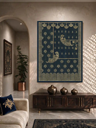 Golden Crest peacock wall art in midnight blue and gold hung above a dark wood sideboard with bronze vases, beside a cream sofa and blue embroidered cushion in a living room.