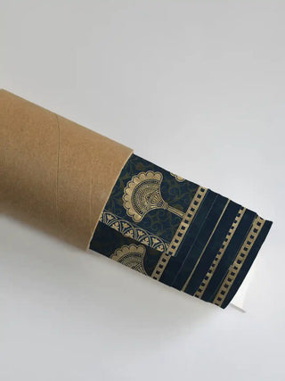Golden Crest wall art print in midnight blue and gold rolled in a kraft shipping tube, showing the gold fan motif and striped border detail.