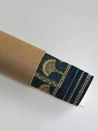 Golden Crest wall art in teal and gold partially unrolled from its kraft paper shipping tube, revealing the gold fan tassel border and blue border detail
