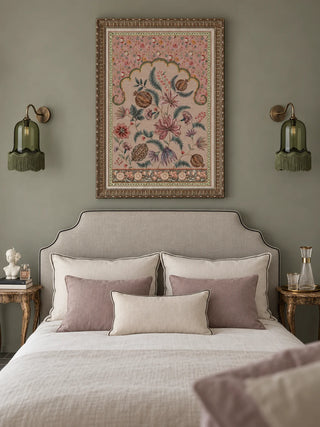 The Golestan Garden wall art framed above an upholstered bed with sage green walls, brass wall sconces and blush linen bedding.