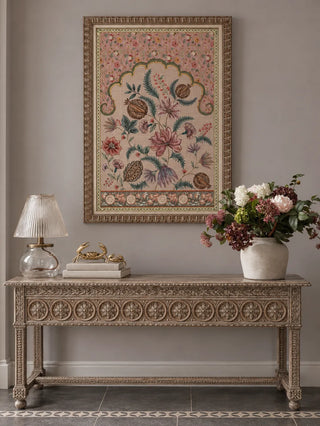 The Golestan Garden wall art framed above a carved console table, styled with a glass lamp, stacked books and a stoneware vase of flowers.