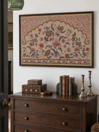 The Golestan wall art in a dark beaded frame above a wooden chest of drawers with inlaid boxes, books and silver candlesticks.