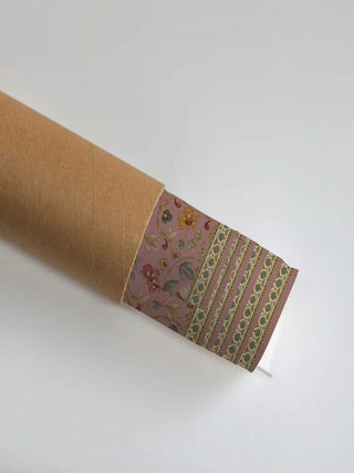 The Golestan Garden wall art print partially unrolled from its kraft paper shipping tube, showing the floral trellis pattern and border.