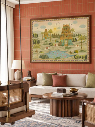 The framed Gopuram wall art displayed above a cream sofa on a terracotta tiled wall, styled with rust and olive cushions.