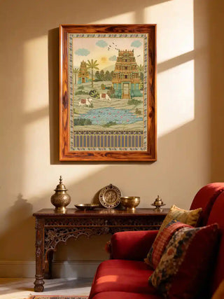 Gopuram temple wall art in sandstone and jade, framed in rosewood above a carved console with brass urns and bowls beside a deep red sofa in a sunlit living room.