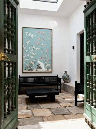 Chinoiserie wall art featuring a white peacock and pink blossoms displayed above a beige tufted sofa in a luxury living room.