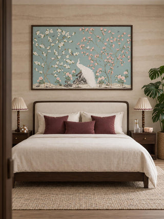 The Grace Embrace embroidered wall art in a dark wood frame above an upholstered bed with burgundy cushions and pleated lamps.