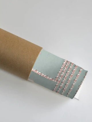 The Grace Embrace wall art partially unrolled from its kraft paper shipping tube, showing an aqua ground with a pink stitched border detail.