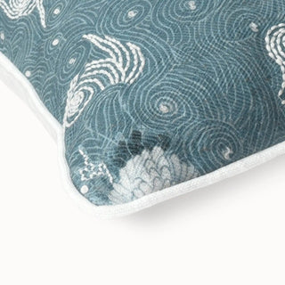 Close-up of the teal cushion corner showing the white embroidery and swirl patterns.