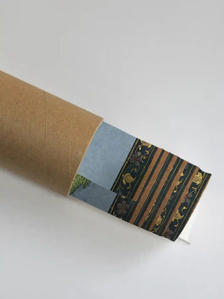 A section of the Green Tara Buddhist painting showing the intricate floral border partially unrolled from its protective shipping tube.