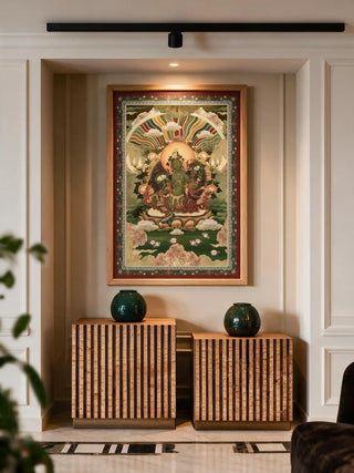 The Green Tara wall art in a wood frame, displayed in a wall niche above two ribbed cork cabinets with dark green ceramic vases.