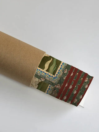 The Green Tara wall art partially unrolled from its kraft paper shipping tube, showing the maroon and green brocade-style border.