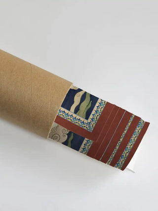The Green Tara wall art partially unrolled from its kraft paper shipping tube, showing the terracotta and patterned guard border.