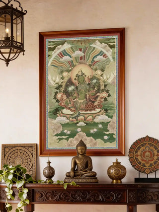A contemplative meditation space featuring the Green Tara painting mounted on a warm wall above a low bench with ritual items.