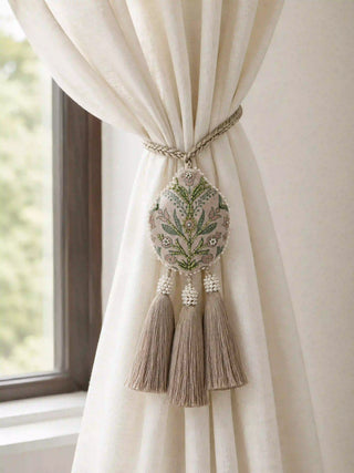 The Gulbano hand-embroidered teardrop tie back gathering a cream linen curtain panel neatly next to a window frame.