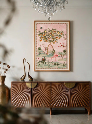 The Gulbiya Chinoiserie wall art in Blush Pink, framed and hung view-entryway above a sunburst-carved wooden console with brass swan figurines.