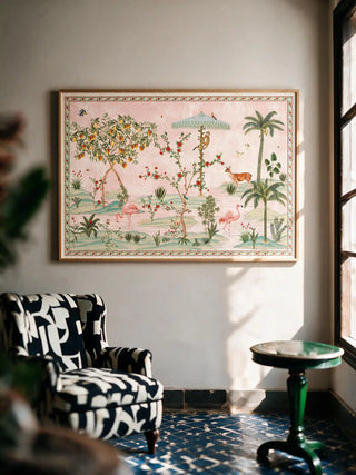 The Gulbiya Chinoiserie wall art in Blush Pink, framed and hung view-livingroom above a printed armchair and green side table.