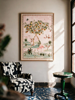 The Gulbiya Chinoiserie wall art in Blush Pink, framed and hung view-livingroom beside a printed armchair and green side table.