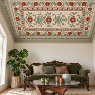 The Gulistan Frieze wallpaper on a living room ceiling above a sage velvet sofa with carved wood arms, a glass coffee table and a potted monstera.