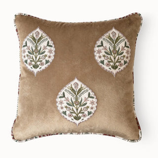 Full front view of the tan velvet Gulmohar Noor Buta Cushion with three embroidered motifs.