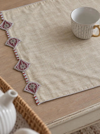 A detailed macro close-up of the Gulnaz table mat highlighting the burgundy teardrop motifs, star flowers and red and white beaded strands.