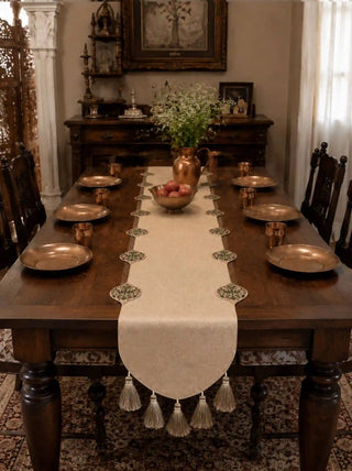The Gulnaz hand-embroidered luxury table runner complete with silk tassels styled symmetrically over a long dark wood festive dining table layout.