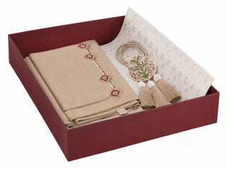 Gulnaz gift set in beige shown at an angle in an open maroon gift box with a folded table runner, embroidered floral tiebacks and tassels on printed tissue